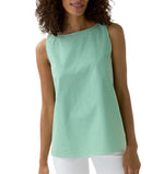 A woman wears the Ann Mashburn Bell Top, a sleeveless green-and-white Italian striped poplin blouse, paired with white pants and standing against a plain white background.