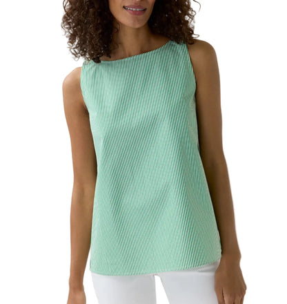 A woman wears the Ann Mashburn Bell Top, a sleeveless green-and-white Italian striped poplin blouse, paired with white pants and standing against a plain white background.