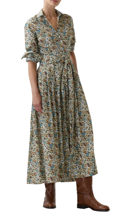 A woman stands against a white background wearing the Ann Mashburn Classic Shirtwaist Rachel Liberty Dress—a long-sleeved, ankle-length dress with a belted waist and a maxi skirt featuring a delicate Liberty Fabrics print—paired with brown knee-high boots for timeless elegance.