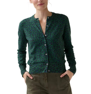An Ann Mashburn Rosie Cotton Silk Leopard Cardigan in green and black is worn with olive green pants, as the woman stands with her hands in her pockets.