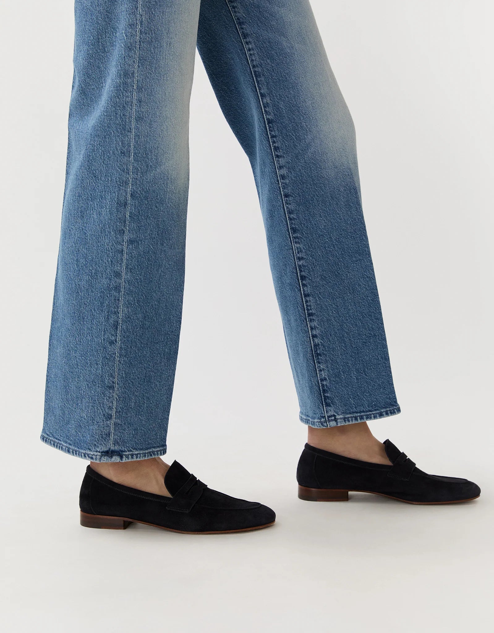 Person wearing blue straight-leg jeans and Ann Mashburn’s Mia Suede Loafer, standing against a plain background.