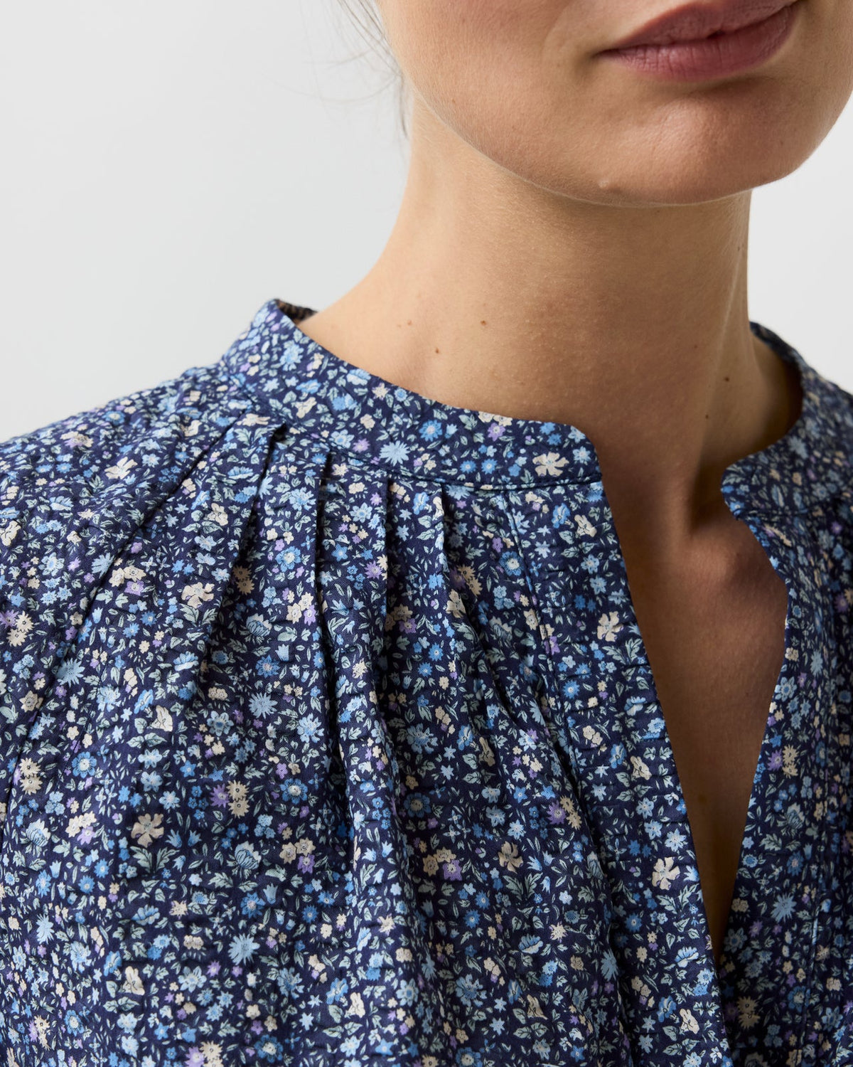 Close-up of the Sienna Crinkle Cotton Top, a blue floral print billowy blouse with a split neckline, pleated shoulder details, and romantic sleeves.