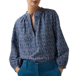 The Ann Mashburn Sienna Crinkle Cotton Top is a long-sleeved, blue floral print blouse in Japanese crinkle cotton, featuring a split neckline, romantic sleeves, and gathered shoulders.