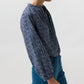 A woman wearing the Sienna Crinkle Cotton Top, a billowy, navy blue floral print blouse with romantic sleeves and a split neckline, paired with teal trousers.