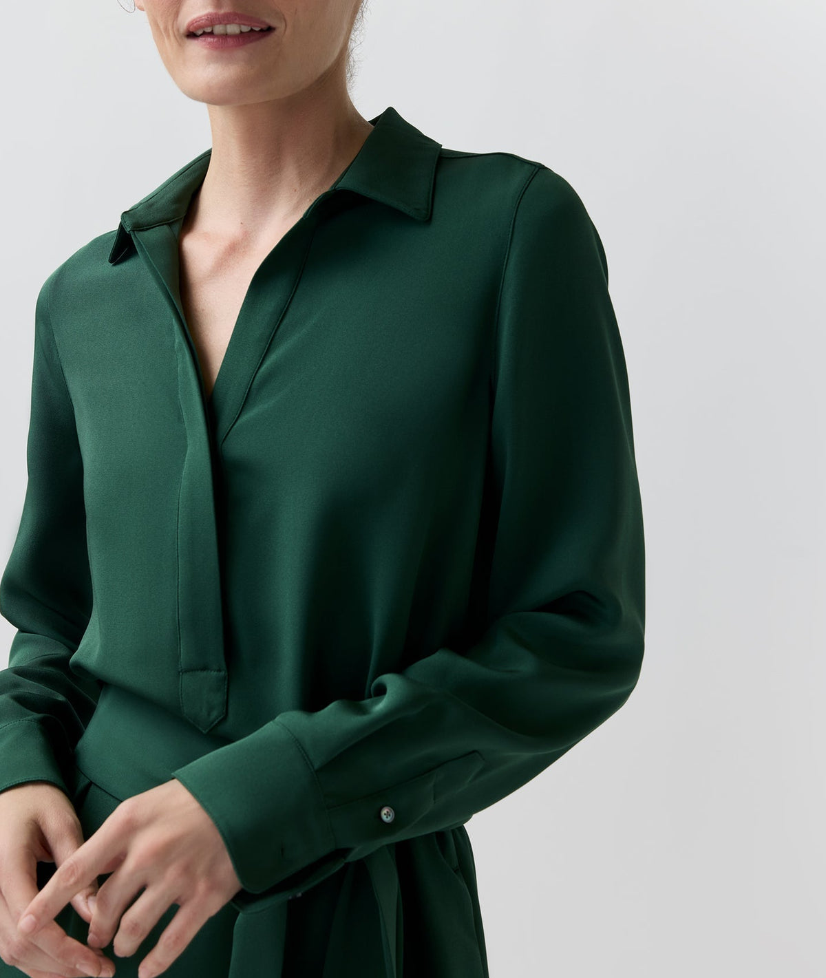 A person wearing a dark green Piper Silk Crepe Maxi Dress in a lightweight crepe de chine with a collared V-neck, long sleeves, and buttoned cuffs.
