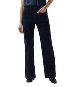 A person wearing Ann Mashburn Camille Patch-Pocket Stretch Corduroy Jean in dark blue with front patch pockets and black loafers.