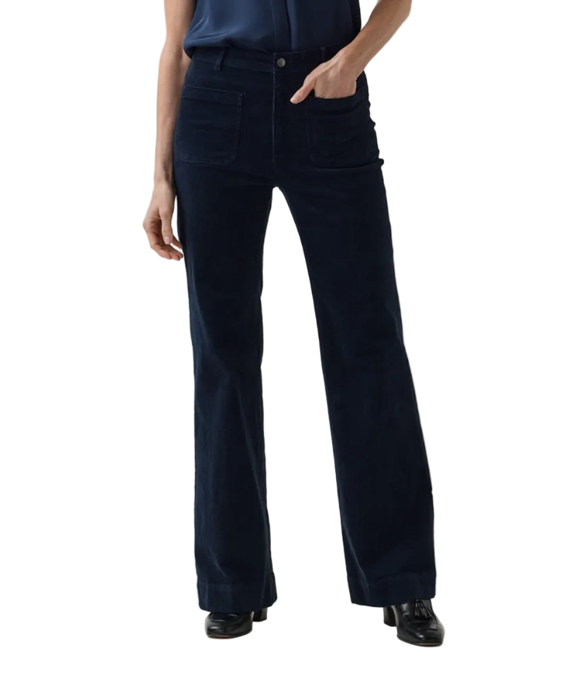 A person wearing Ann Mashburn Camille Patch-Pocket Stretch Corduroy Jean in dark blue with front patch pockets and black loafers.
