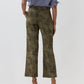 A person wearing the Ann Mashburn Frankie Stretch Twill Cropped Pant in green camouflage, featuring a barely-there waistband, paired with a blue and white checkered blouse and tan heeled sandals, stands against a plain light background with their back to the camera.