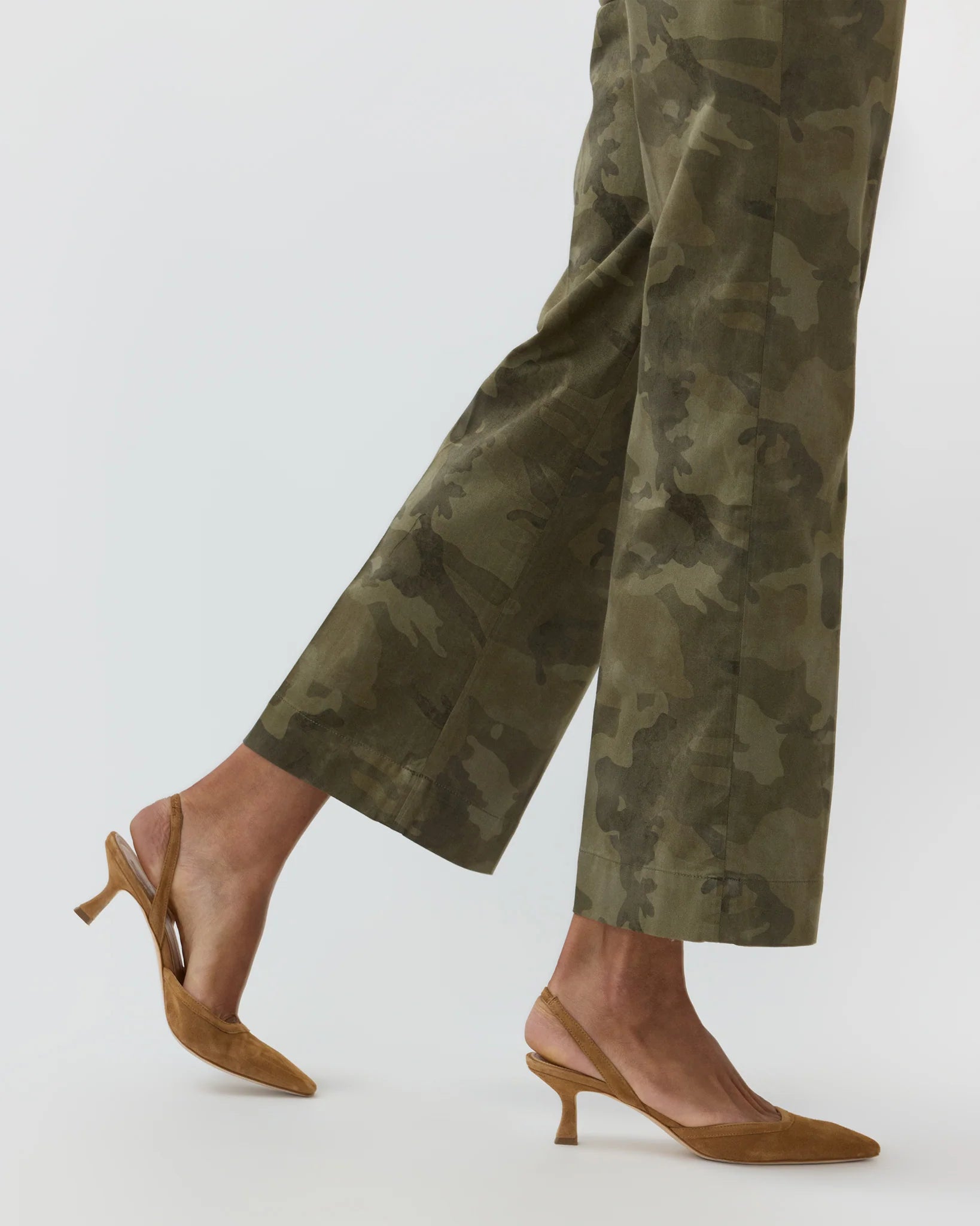 An individual stands against a white background wearing the Ann Mashburn Frankie Stretch Twill Cropped Pant, featuring a barely-there waistband, paired with brown slingback kitten heels.