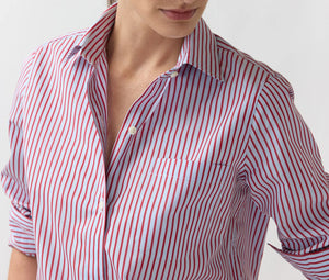 A person is wearing the Ann Mashburn Sidney Banker Stripe Poplin Shirt, a red and white vertically striped button-up made from Italian poplin with a spread collar and rolled-up sleeves, shown from the shoulders to the waist against a plain background.