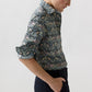 A person wearing an Ann Mashburn Tomboy Popover Liberty Shirt with a dark floral and bird print, featuring rolled-up sleeves and a relaxed fit.