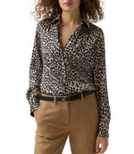 A woman wears a leopard print Natalia Silk Blouse tucked into tan trousers with a black leather belt.
