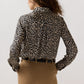 Back view of an Ann Mashburn Natalia Silk Blouse in a classic leopard print, tucked into tan trousers with a black belt.