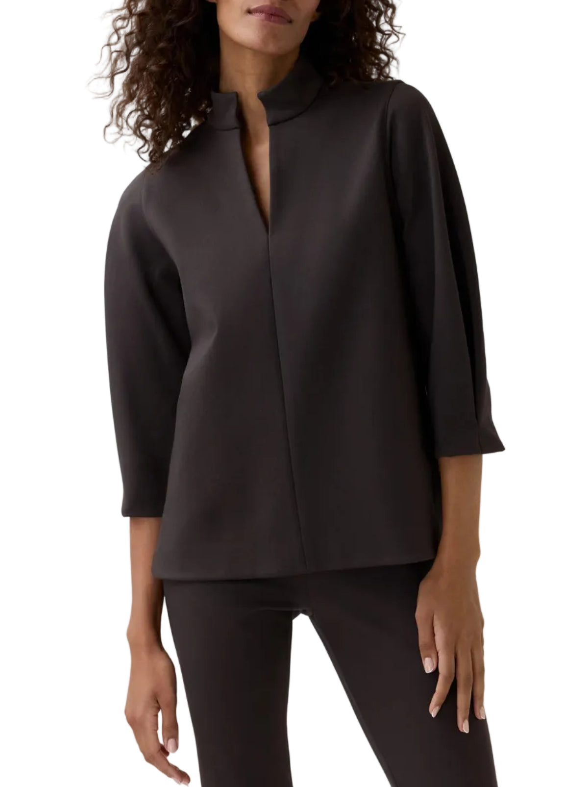 A woman wearing the Ann Mashburn Violetta Bi-Stretch Tricotine Tunic—a dark brown top featuring a stand collar and quarter-length sleeves—paired with matching pants for a modern look that blends comfort and sophisticated style.