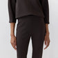 A person wearing Ann Mashburn’s Faye Flare Cropped Pant in dark brown with a matching long-sleeve blouse, standing against a plain light background.