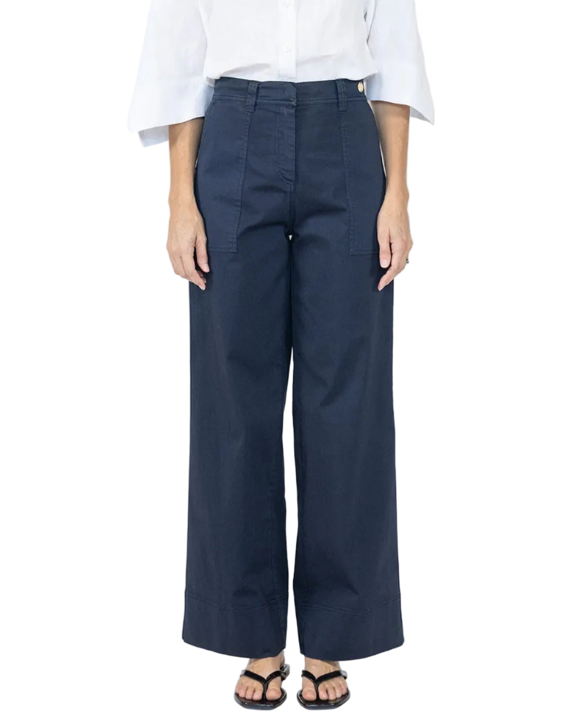 A person wearing a white blouse, black sandals, and Callas Milano Sailor Pant in navy cotton twill with front seams stands against a plain background.