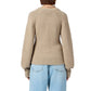 Model wearing the Sculpted Cardigan by Guest in Residence—a beige cropped, puff-sleeve knit—paired with light blue jeans, shown from the back against a plain background.