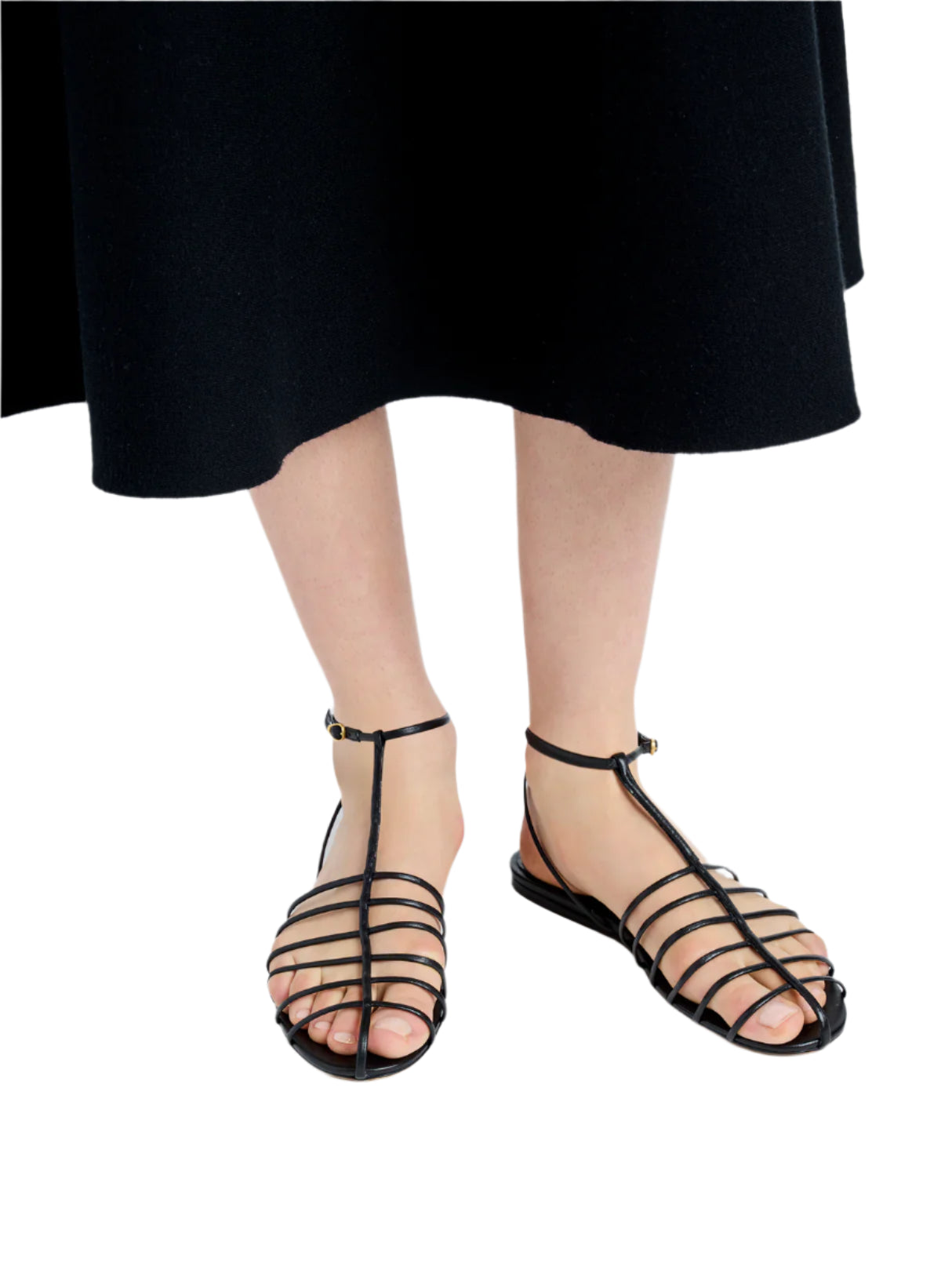 The person is wearing a black skirt paired with Proenza Schouler Tee Cage Flat Sandals featuring elegant t-crossed straps for a stylish caged silhouette.