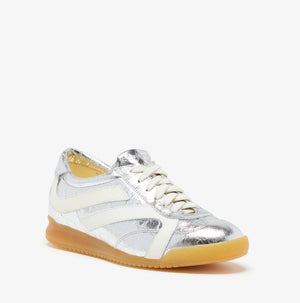 The Proenza Schouler Track Crinkled Metallic Sneakers feature silver leather, white side stripes and laces, a tan rubber sole, and a memory foam insole, shown on a plain white background.