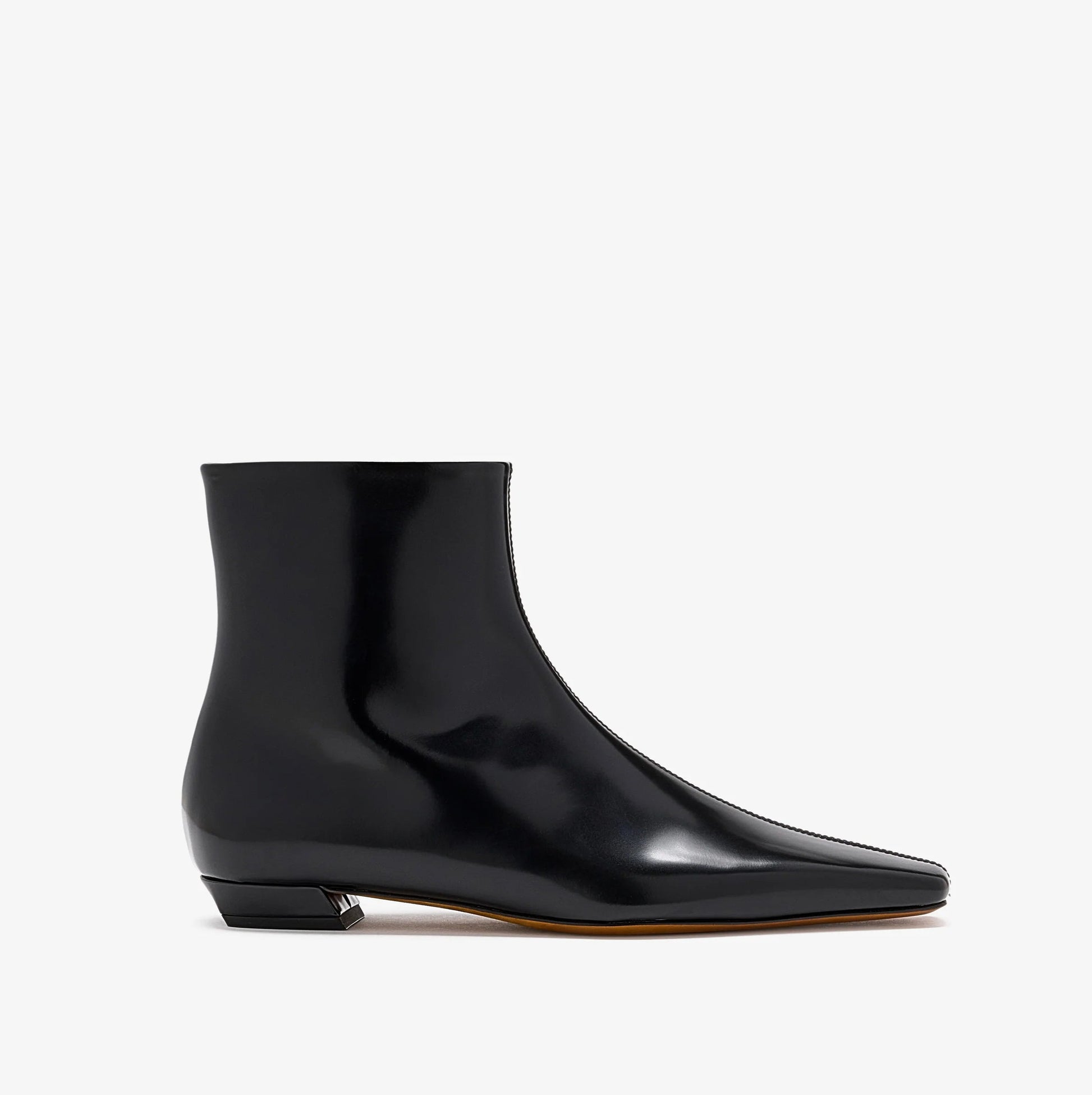 The Proenza Schouler Trap Flat Ankle Boots feature black nappa leather with a pointed toe, low square heel, and glossy finish, shown from the side against a plain white background.