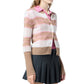 A woman wears the Guest in Residence Shadow Plaid Cardigan over a pink collared shirt, paired with a dark pleated skirt.