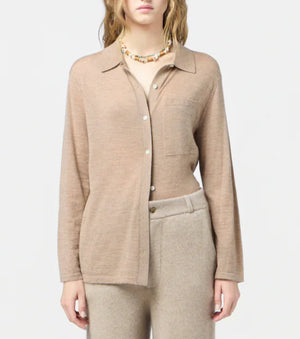 A person wearing the beige Showtime Cashmere Shirt by Guest in Residence with matching pants and a beaded necklace stands against a plain light background.