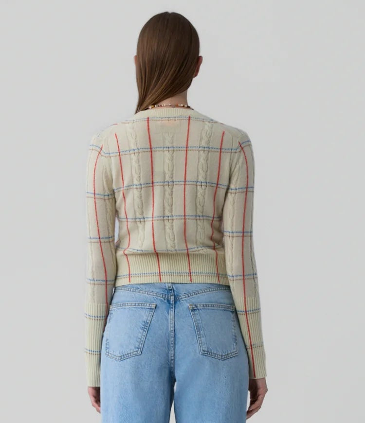 A person faces away from the camera wearing Guest in Residence’s Shrunken Check Crew and high-waisted blue jeans against a plain background.