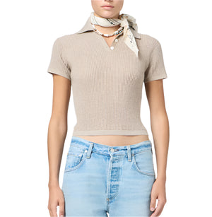 A person wearing the Guest in Residence Shrunken Cashmere Polo in beige, paired with light blue jeans, a light-colored neck scarf, and a beaded choker necklace.