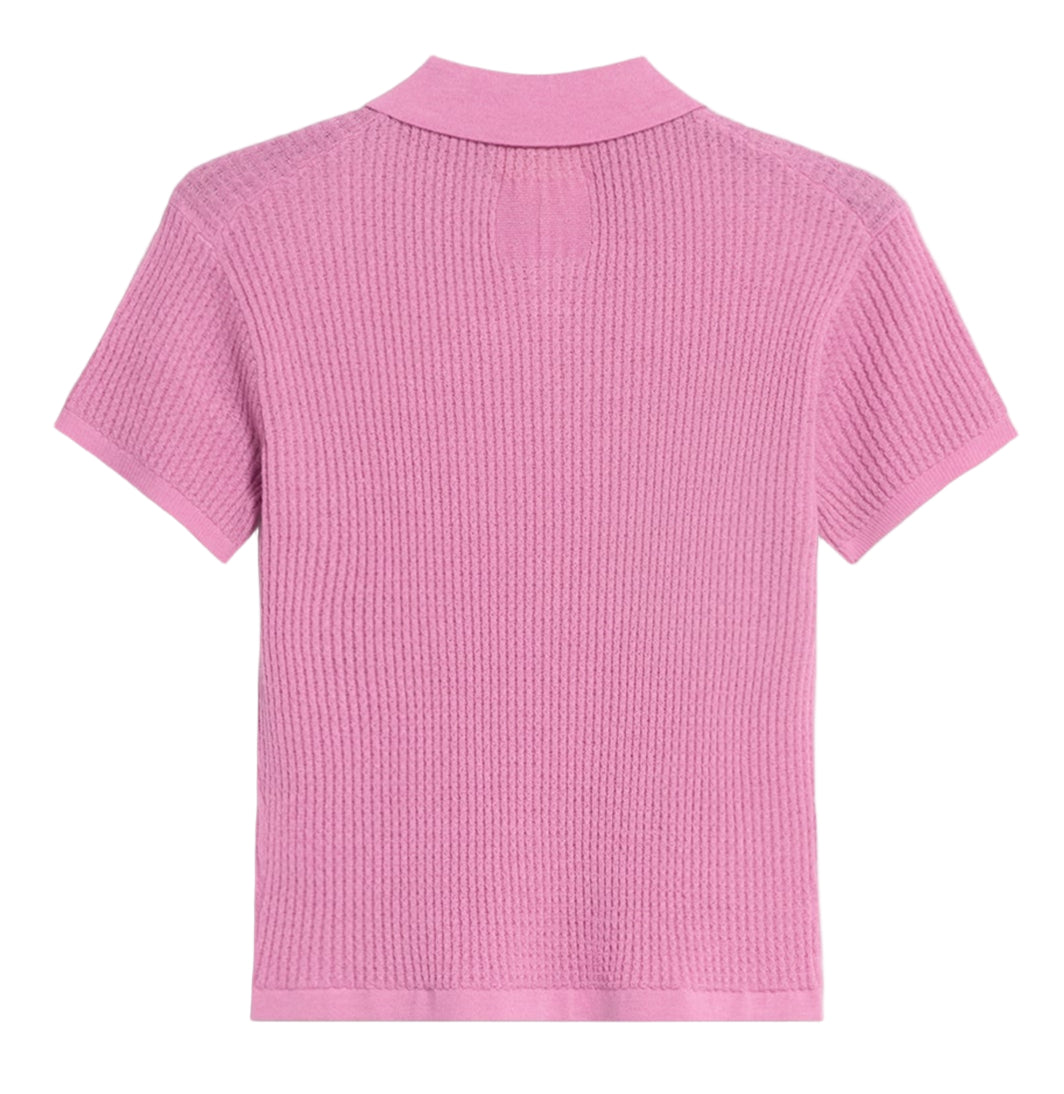 The Shrunken Cashmere Polo by Guest in Residence is displayed from the back. This short-sleeved, ribbed, light pink lightweight shirt stands out against a white background.