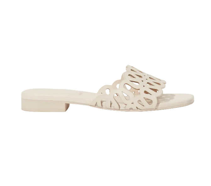 The Simkhai McCall Laser Cut Flat Slide is a beige supple leather sandal with an open toe, low heel, and a decorative upper strap featuring swirling laser perforations and softly scalloped edges.