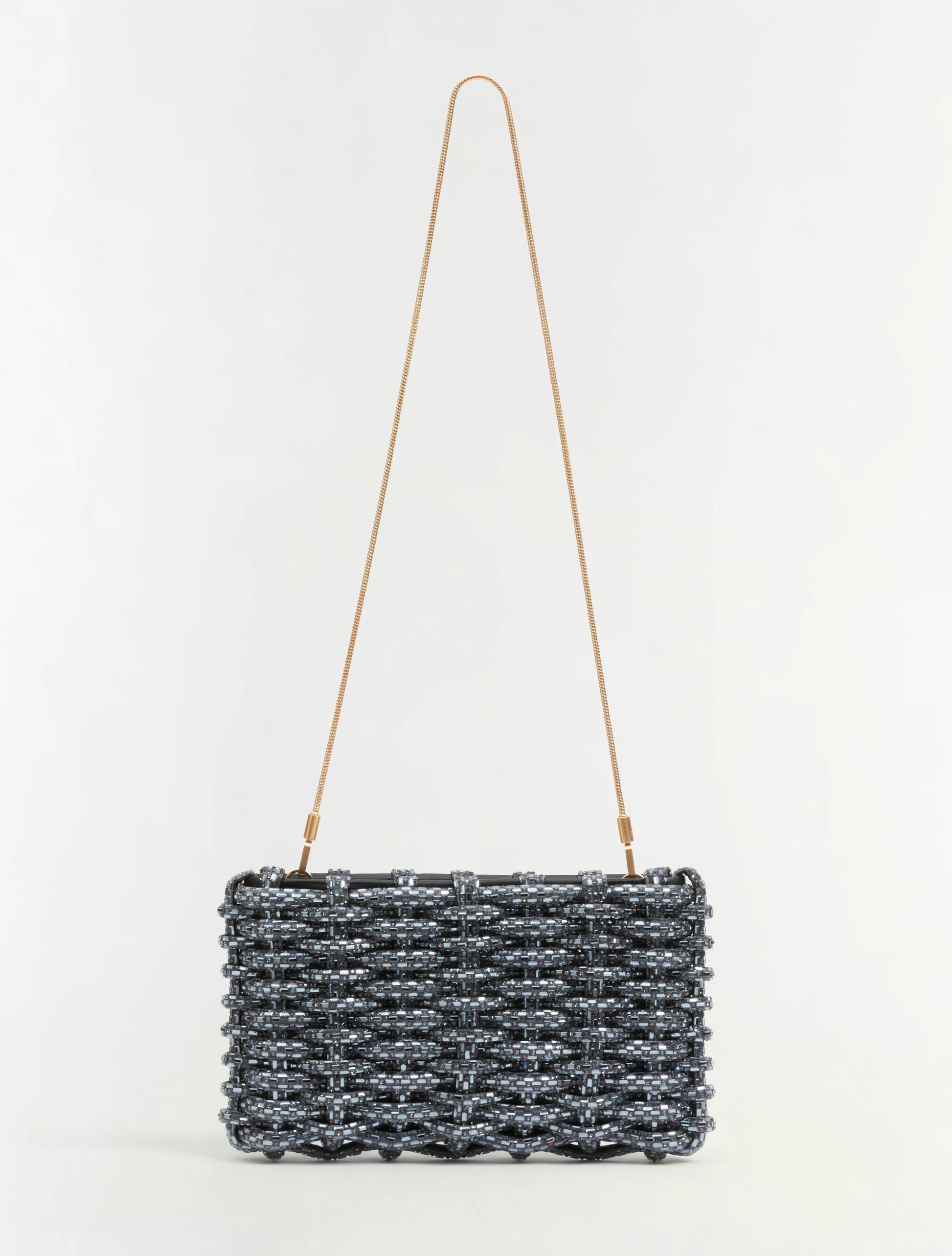 The Simkhai Morgan Clutch is a rectangular woven black and silver handbag featuring a thin, long gold shoulder strap, displayed against a plain white background.