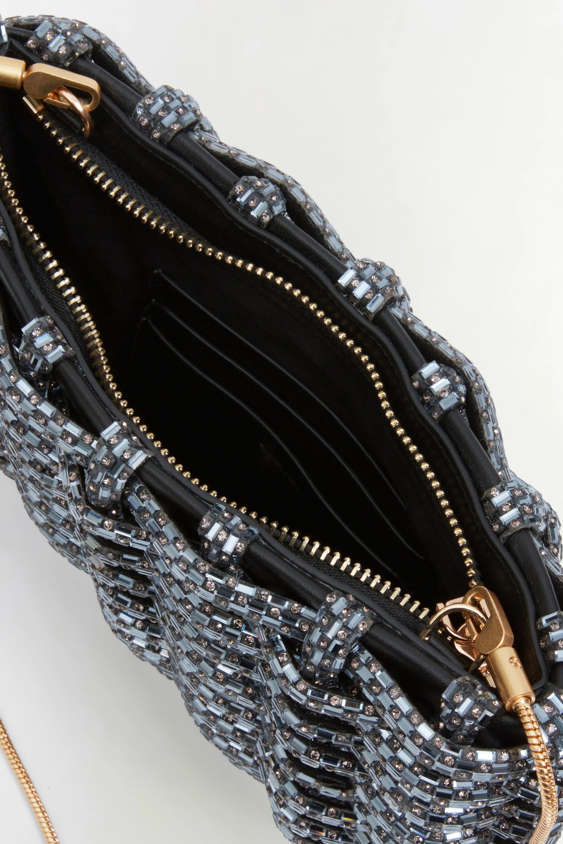 Close-up of an open Simkhai Morgan Clutch, featuring a beaded exterior, gold zipper, black interior, and visible card slots inside.
