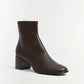 The Bianca Stretch Leather Ankle Boot by Simkhai is a dark brown ankle boot featuring a rounded toe and a low, chunky block heel, shown against a plain white background.