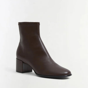 The Bianca Stretch Leather Ankle Boot by Simkhai is a dark brown ankle boot featuring a rounded toe and a low, chunky block heel, shown against a plain white background.