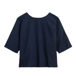 The Saria Top by Suzie Kondi is a loose-fit, dark blue linen shirt with a chic silhouette, round neckline, and elbow-length sleeves displayed on a white background.