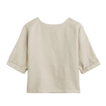 The Saria Top by Suzie Kondi is a beige linen shirt featuring a wide round neckline, elbow-length cuffed sleeves, and a loose, boxy fit. Minimalist and versatile, it has no visible buttons or patterns, showcasing a chic silhouette.