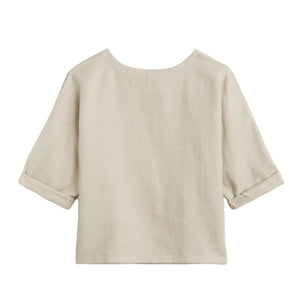 The Saria Top by Suzie Kondi is a beige linen shirt featuring a wide round neckline, elbow-length cuffed sleeves, and a loose, boxy fit. Minimalist and versatile, it has no visible buttons or patterns, showcasing a chic silhouette.