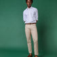 A man stands against a green background wearing a white dress shirt with rolled sleeves, Sid Mashburn Clift Straight Leg Jeans, a brown belt, and brown shoes.