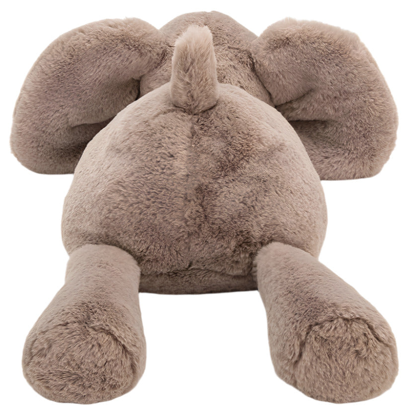 A Jellycat Smudge Elephant, Medium—crafted from soft brown fur—lies face-down with splayed ears and outstretched legs, resembling a sleepy elephant after a busy day.