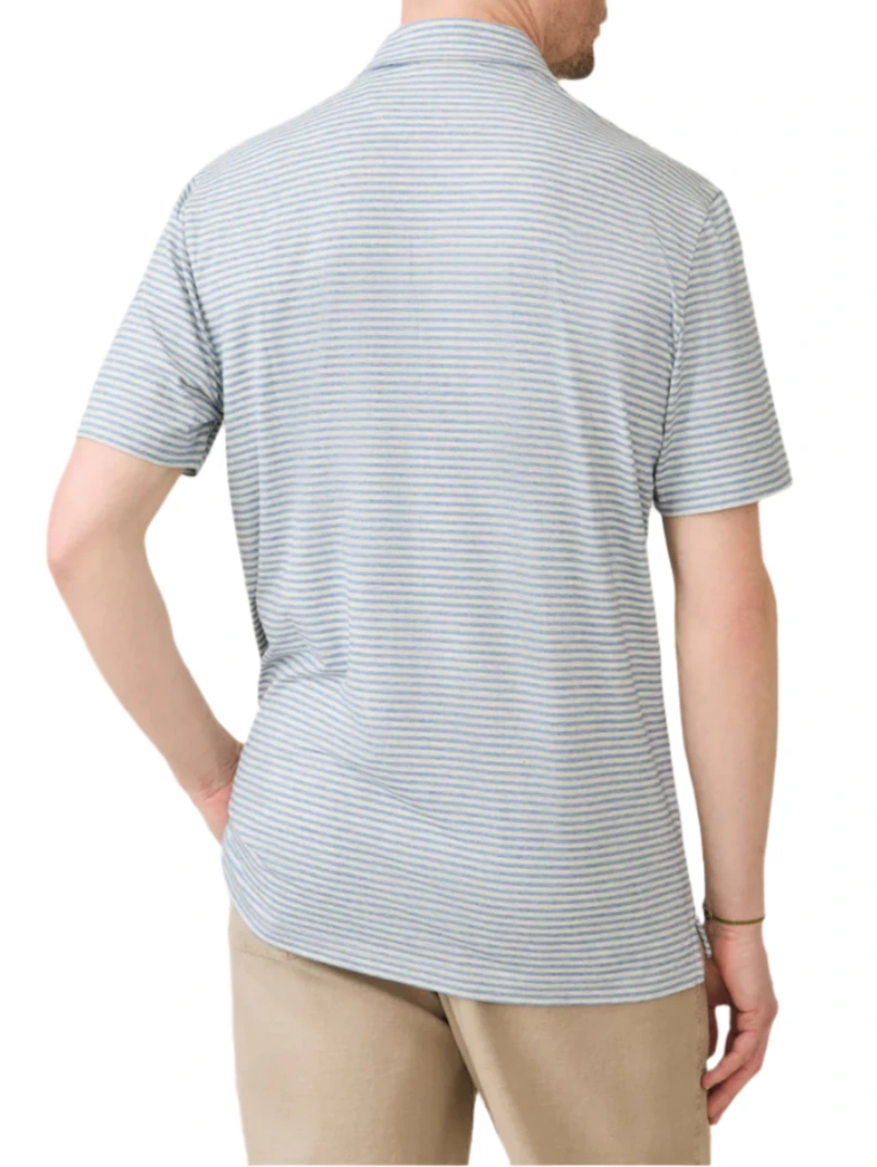 A person is seen from behind wearing Faherty's Short-Sleeve Movement™ Polo Shirt in light blue and white stripes with beige pants, hand resting on hip. This polo combines effortless movement with comfort and style.