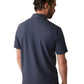 A man with short curly hair, wearing a dark Faherty Sunwashed T-Shirt Polo made from regenerative organic cotton and jeans, is seen from the back against a white background.