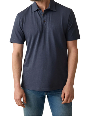 A person wearing a Faherty Sunwashed T-Shirt Polo and blue jeans, standing against a white background.