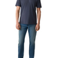 A man stands facing forward against a white background wearing a navy Sunwashed T-Shirt Polo by Faherty, blue jeans, and white sneakers.