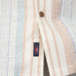 The Short-Sleeve Breeze Camp Shirt by Faherty features light striped fabric with pastel pink, blue, and beige vertical lines. A small logo tag near a brown button suggests a loose fit. This perfectly crafted cool cotton blend is ideal for summer dreams.