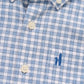 Close-up of the Johnnie-O Boys' Performance Jr. Button Up Shirt Westwood Print, featuring a blue and white plaid pattern, Tweener® button, white buttons, and a small blue embroidered chest design.