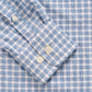 A close-up of the Johnnie-O Boys' Performance Jr. Button Up Shirt in Westwood Print, featuring blue and white checks, three white cuff buttons, and wrinkle-resistant comfort.