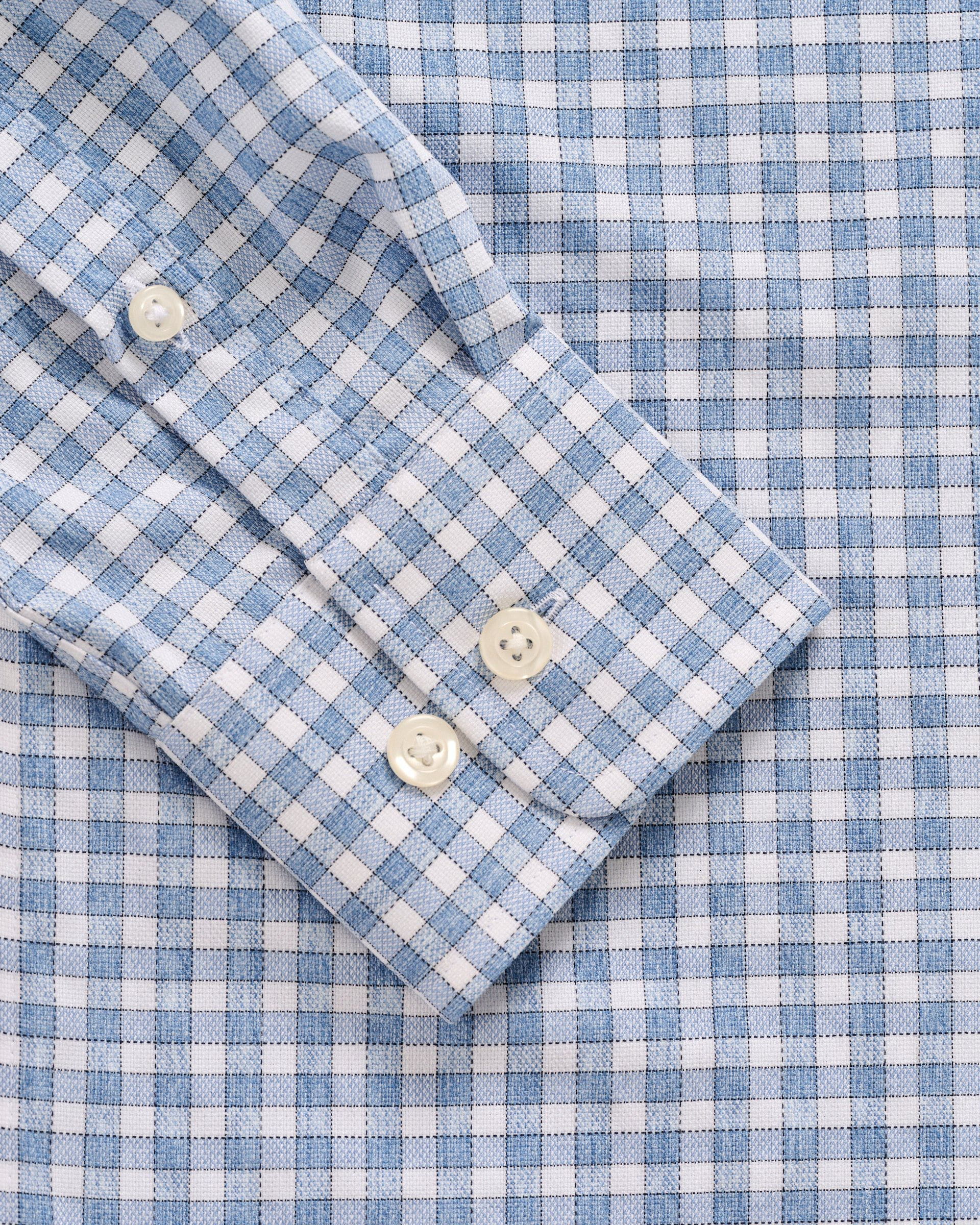A close-up of the Johnnie-O Boys' Performance Jr. Button Up Shirt in Westwood Print, featuring blue and white checks, three white cuff buttons, and wrinkle-resistant comfort.