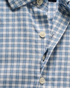 Close-up of the Johnnie-O Westwood Button Down, a blue and white checkered performance dress shirt featuring white buttons, a classic collar, and detailed fabric texture and pattern.