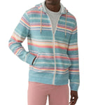 A person wearing a Faherty's Whitewater Full Zip Hoodie over a gray shirt and pink pants stands with one hand in the pocket.