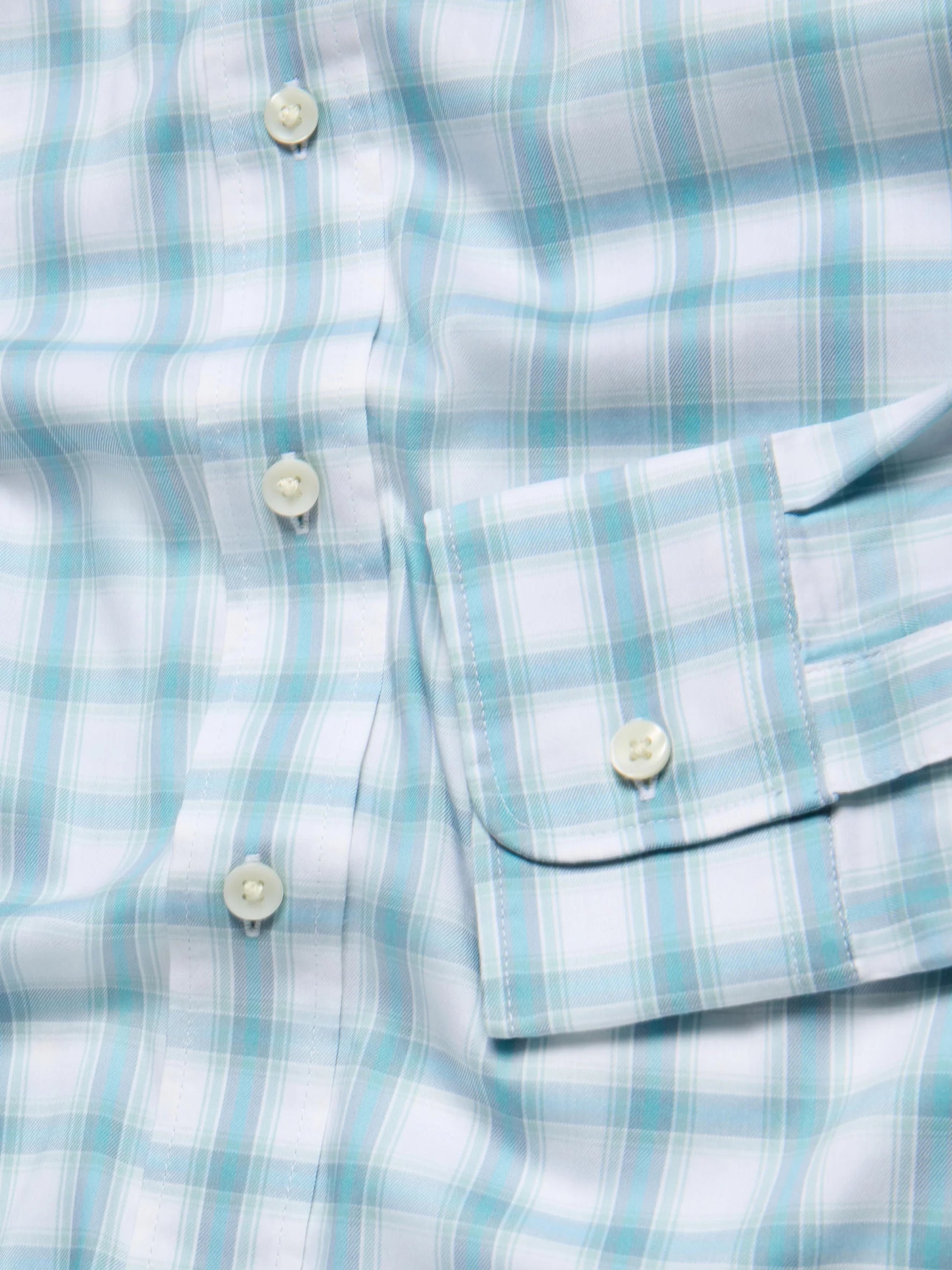 Close-up of The Movement Shirt by Faherty, showcasing a light blue and white plaid design with white buttons and neatly folded cuffs, crafted from soft Supima Cotton.